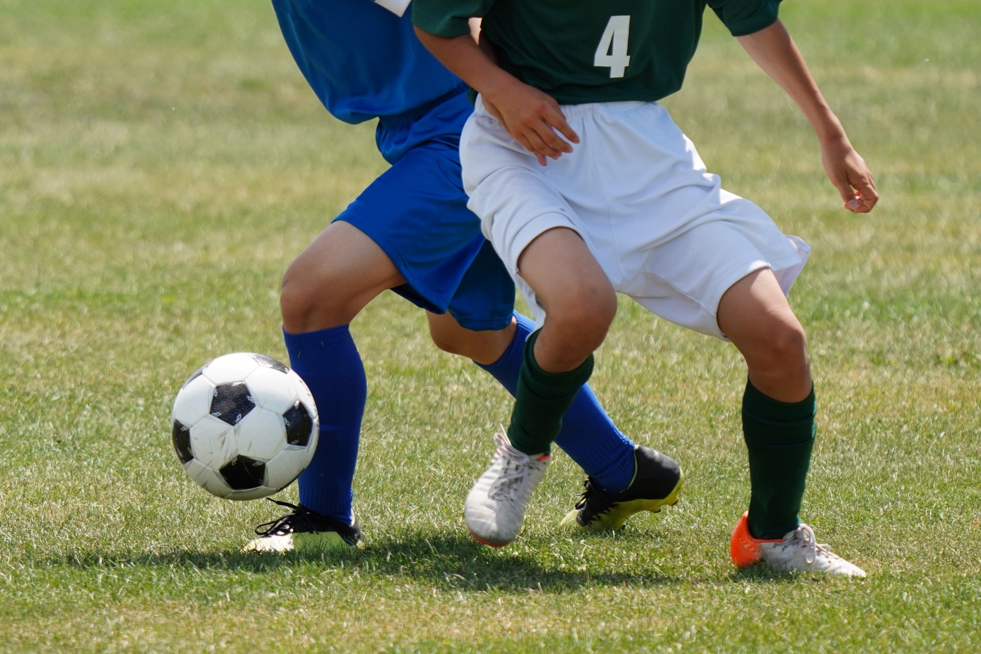 サッカーグラウンドで元気にボールを追いかけて走る10歳前後の男の子